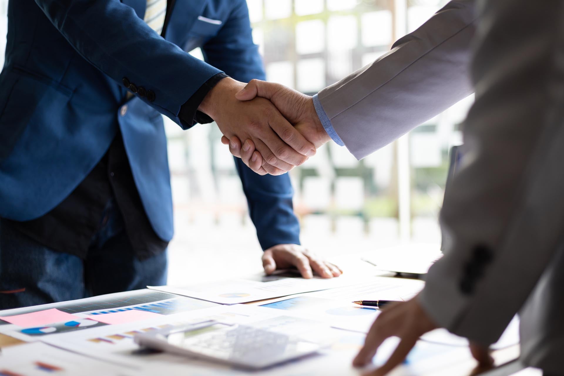 business men shaking hands documents table