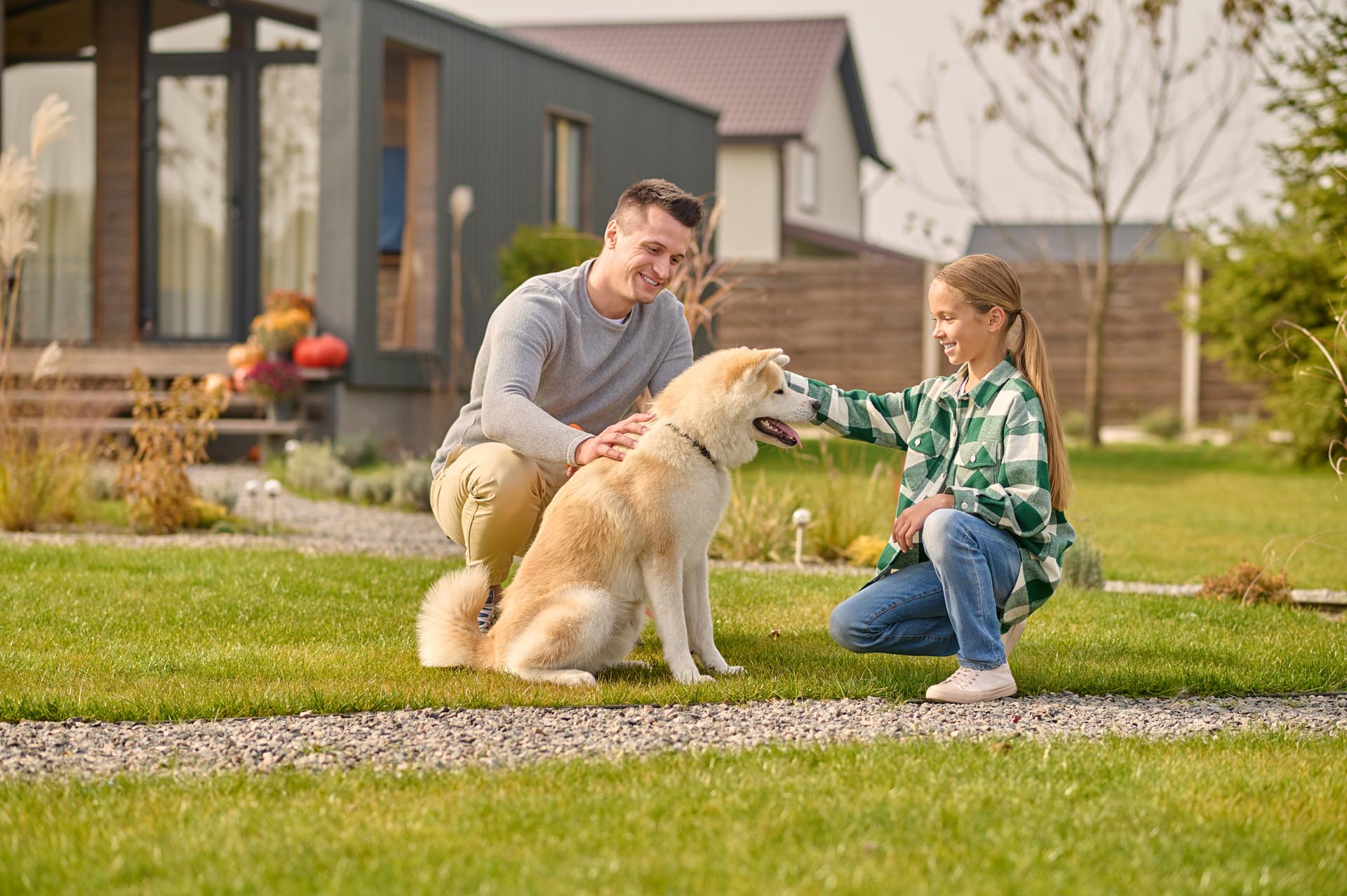 dad daughter petting dog in yard